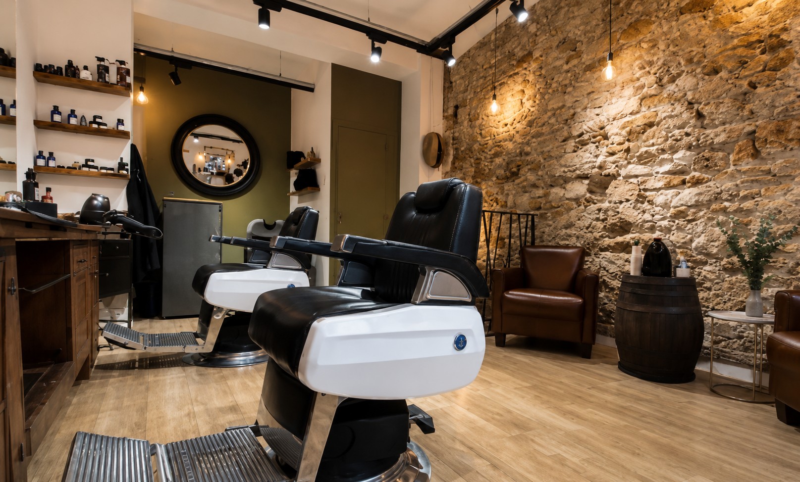 Mur en pierre apparente, fauteuils de barbier et fauteuils en cuir cognac